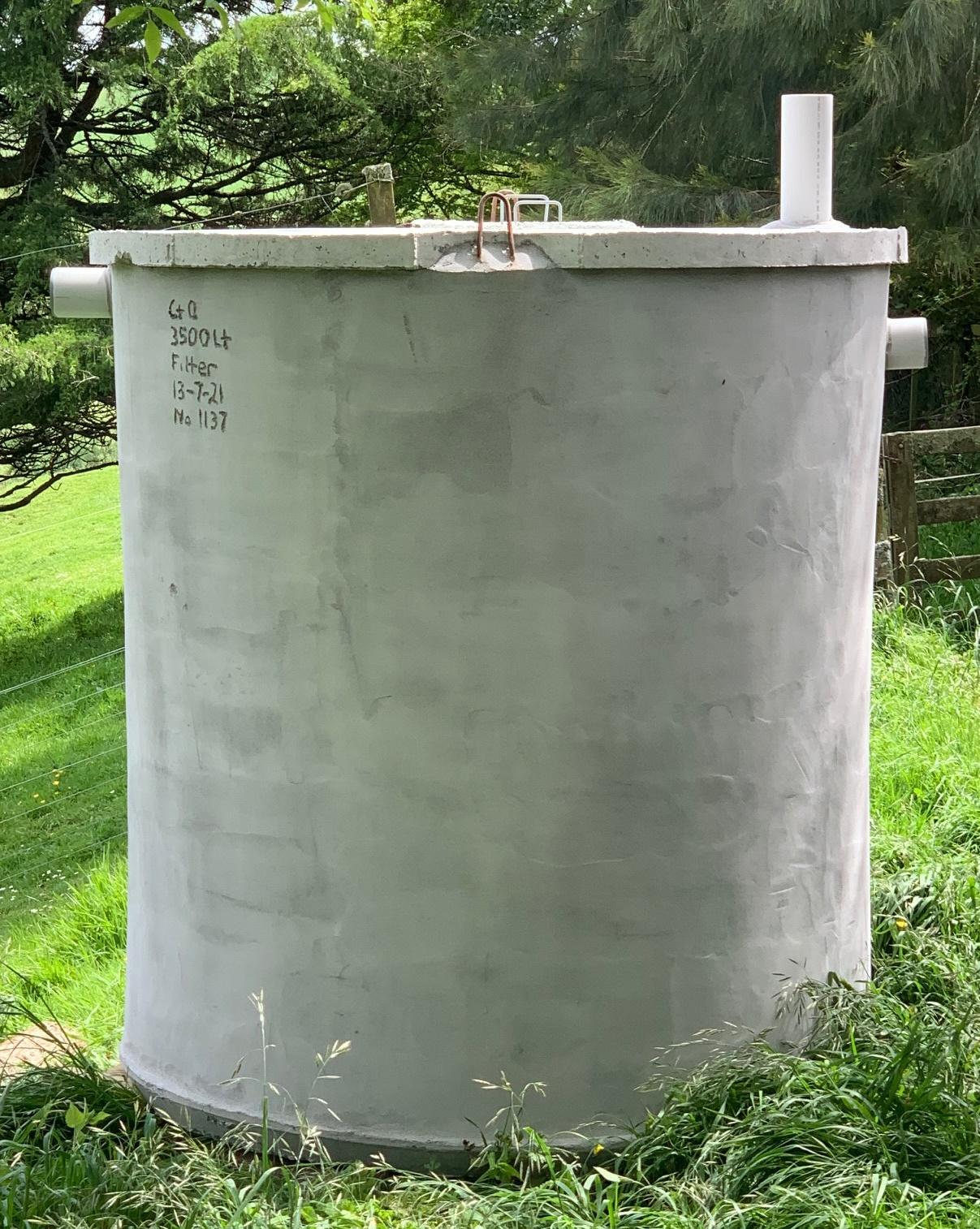 Tall cylindrical concrete septic tank standing in grass
