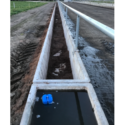 Long oblong concrete water trough along a stock rail