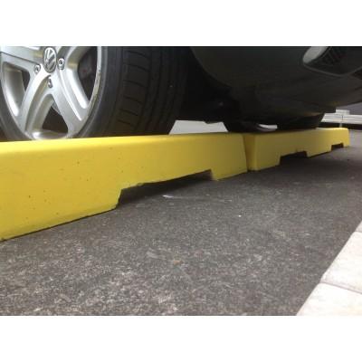 Yellow concrete wheel stops under a parked car