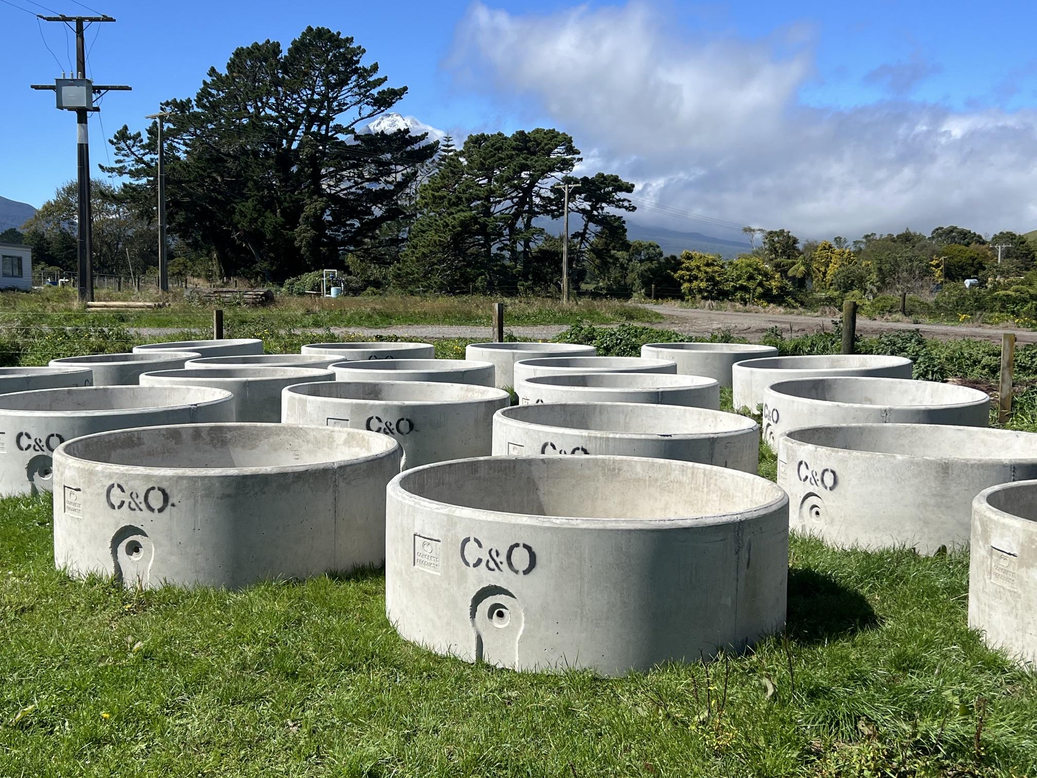 Round concrete water troughs stamped C&O in a green Taranaki paddock